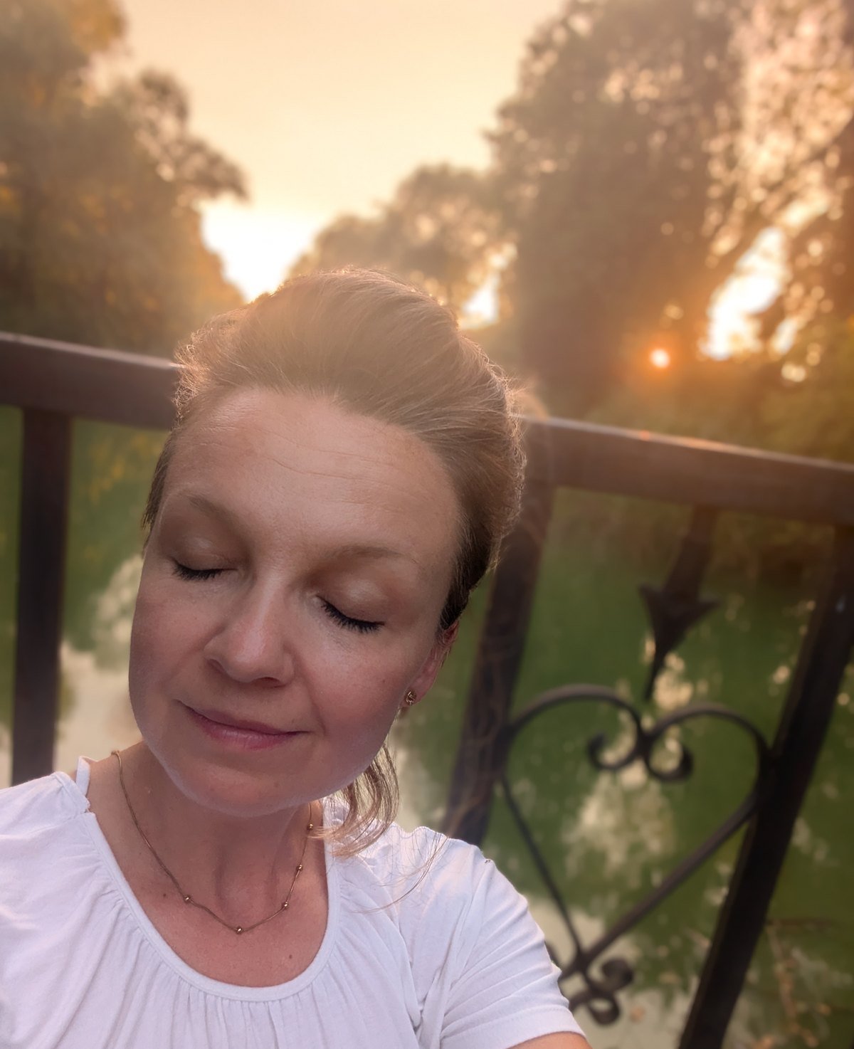 Joanna Rosikoń z zamkniętymi oczami, w świetle zachodzącego słońca.